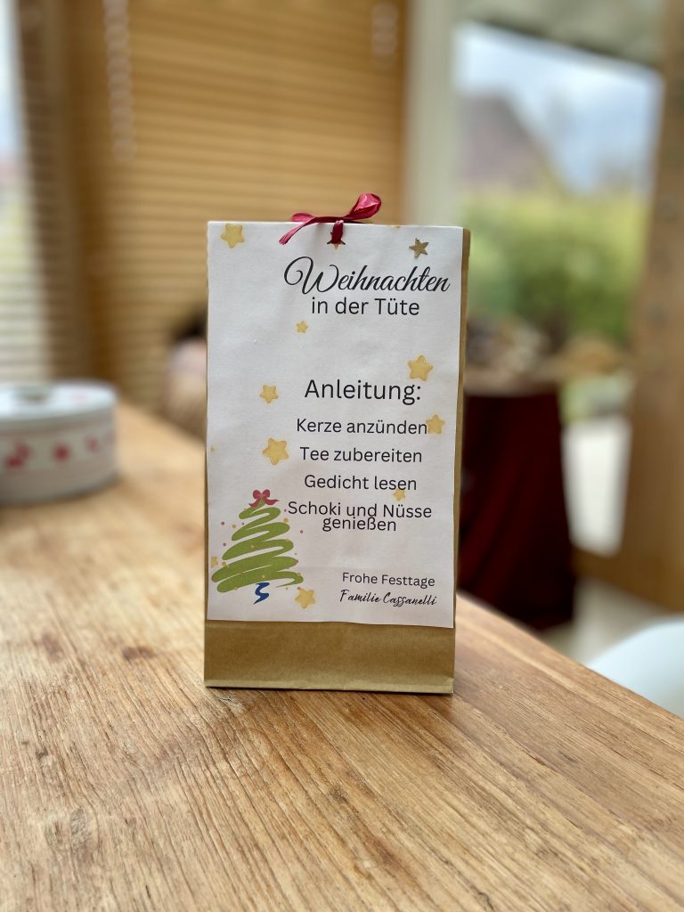 Eine klein Geschnektüte mit der Aufschrift: Weihnachten in der Tüte. Anleitung: Kerze anzünden, Teee zubereiten, Gedicht lesen, Schocki und Nüsse genießen.