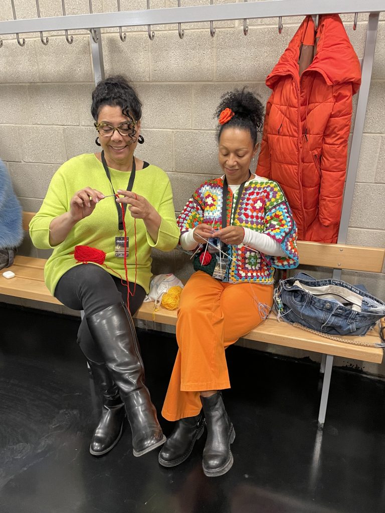 Zwei Frauen häkeln und strickenEine Frau macht eine Häkelrose, die andere Frau strickt Socken