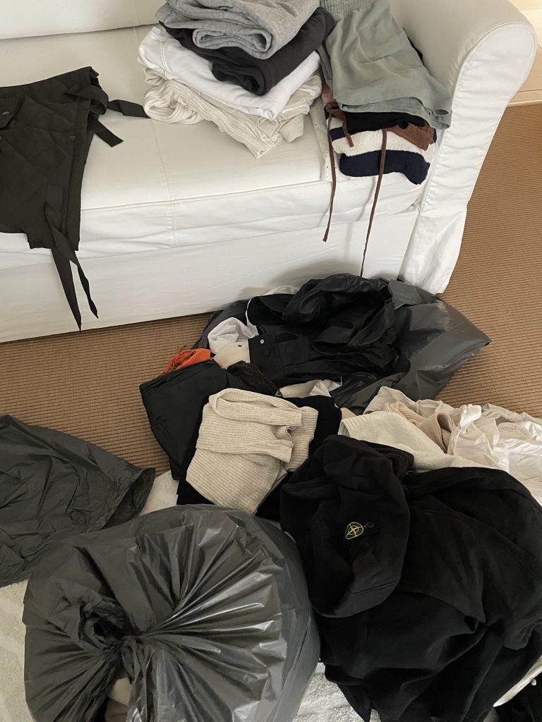 viele Kleidungsstücke auf dem Boden und Sofa. Sie werden sortiert