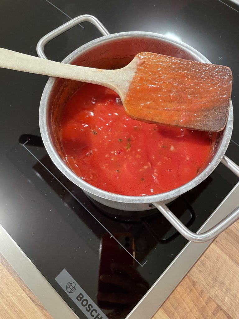 Tomatensoße auf dem neuen Herd in einem Topf
