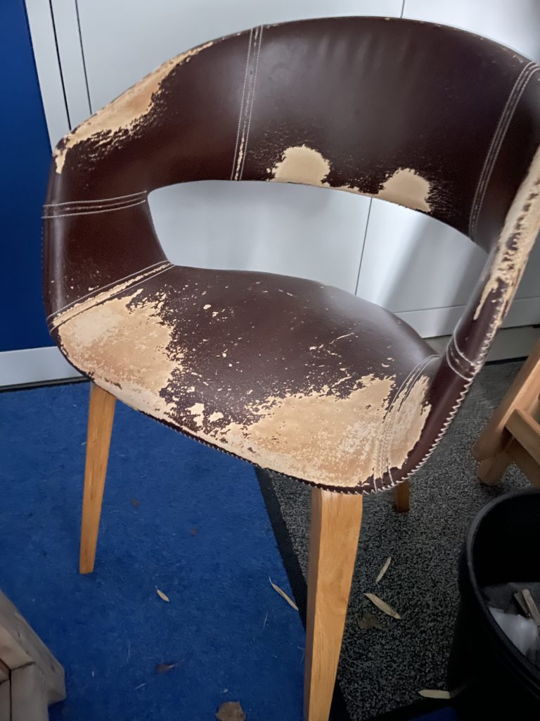 ein alter Stuhl dessen Sitzfläche sehr abgewetzt ist