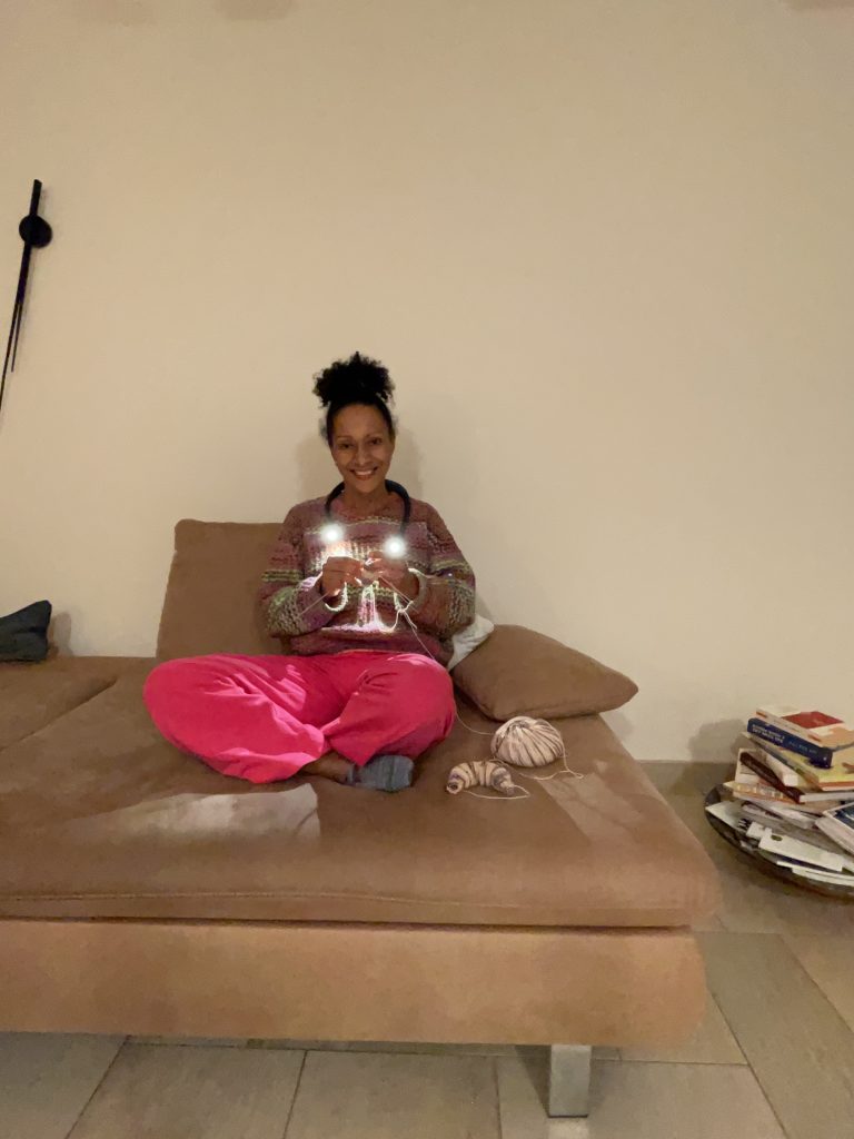 eine Frau sitzt strickend auf einem Sofa