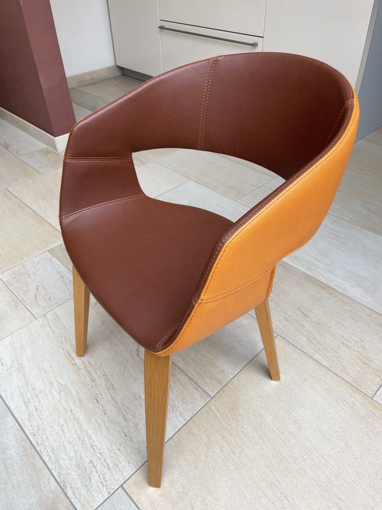 Ein Stil dessen Rückseite orangefarben ist und die Vorderseite braun. Die Beinen sind aus Holz