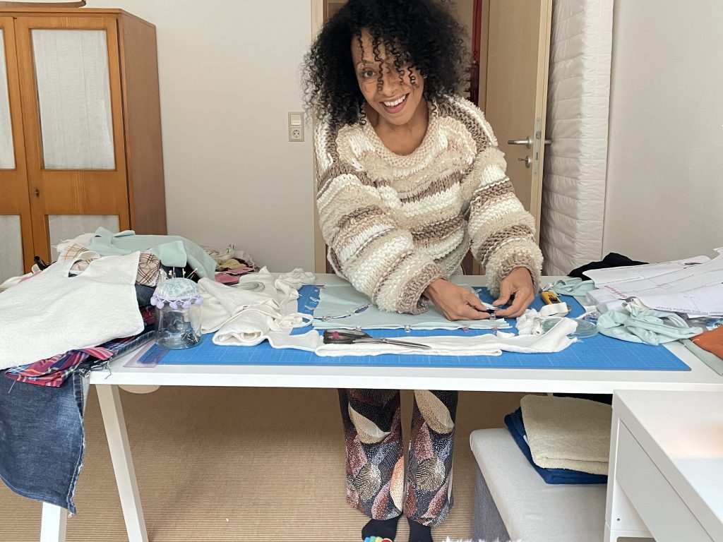 Eine Frau steht an einem Zuschneidetisch und schneidet Stoff zu. Zu sehen im Monatsrückblick März