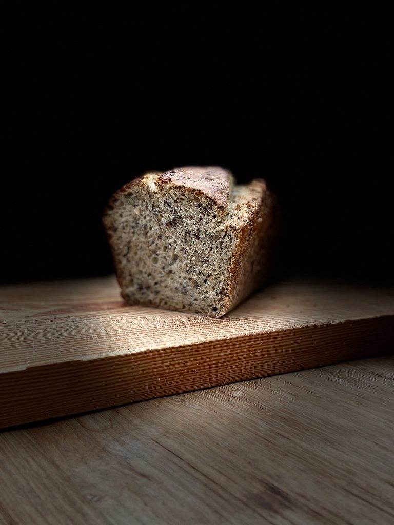 Fertig gebackenes Brot liegt aufgeschnitten auf einem Holzbrett