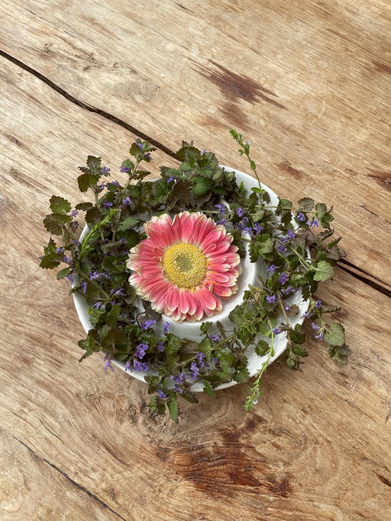 Eine Schale mit Blumen darin auf einem Holztisch