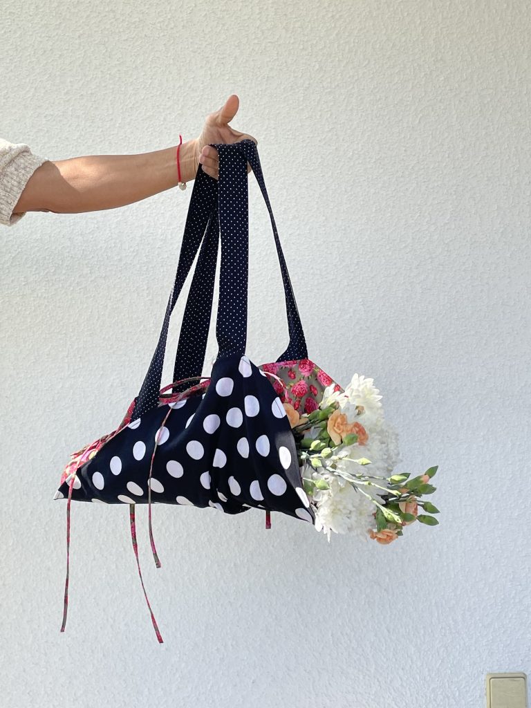 Blumentasche mit Blumen darin wird in Eier Hand gehalten