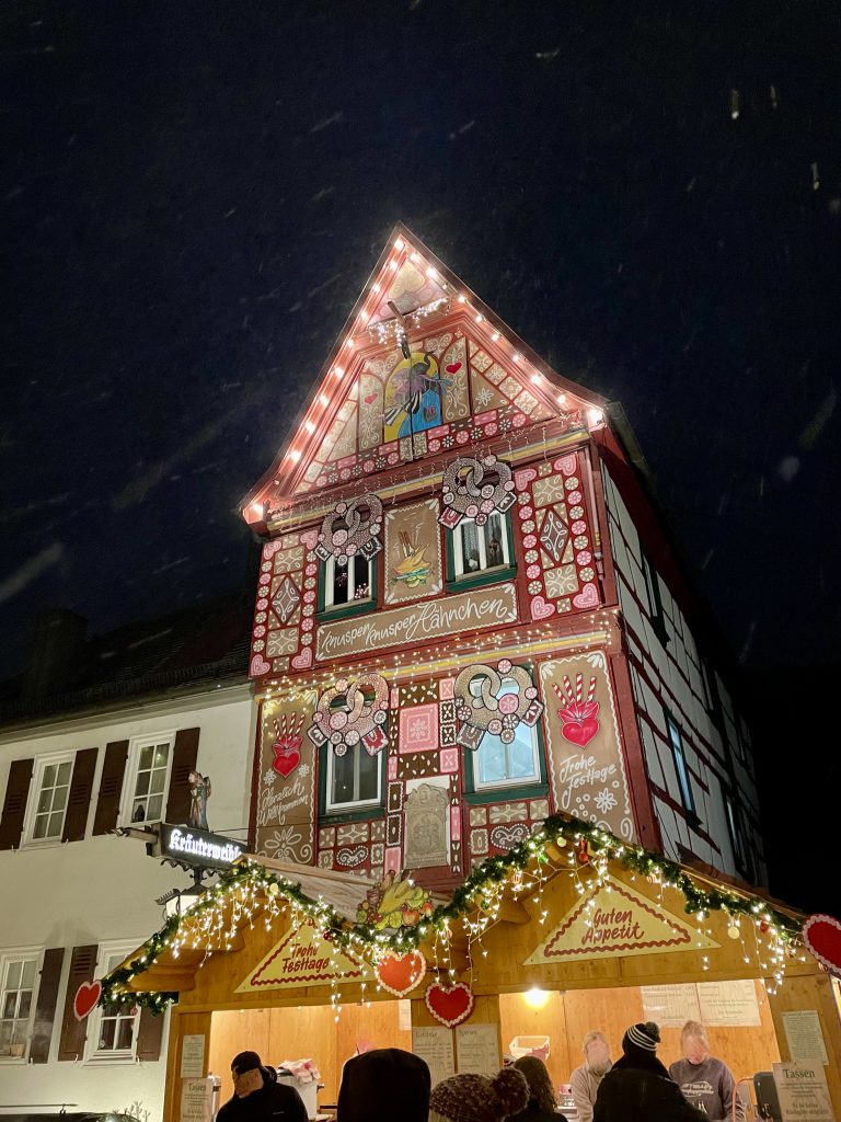 Ein weihnachtlich geschmücktes Fachwerkhaus in Bad Wimpfen. Davor steht eine Weihnachtsmarktstand