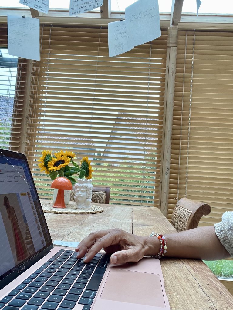 Ein Laptop auf einem Tisch . Im Hintergrund steht ein Sonnenblumenstrauß