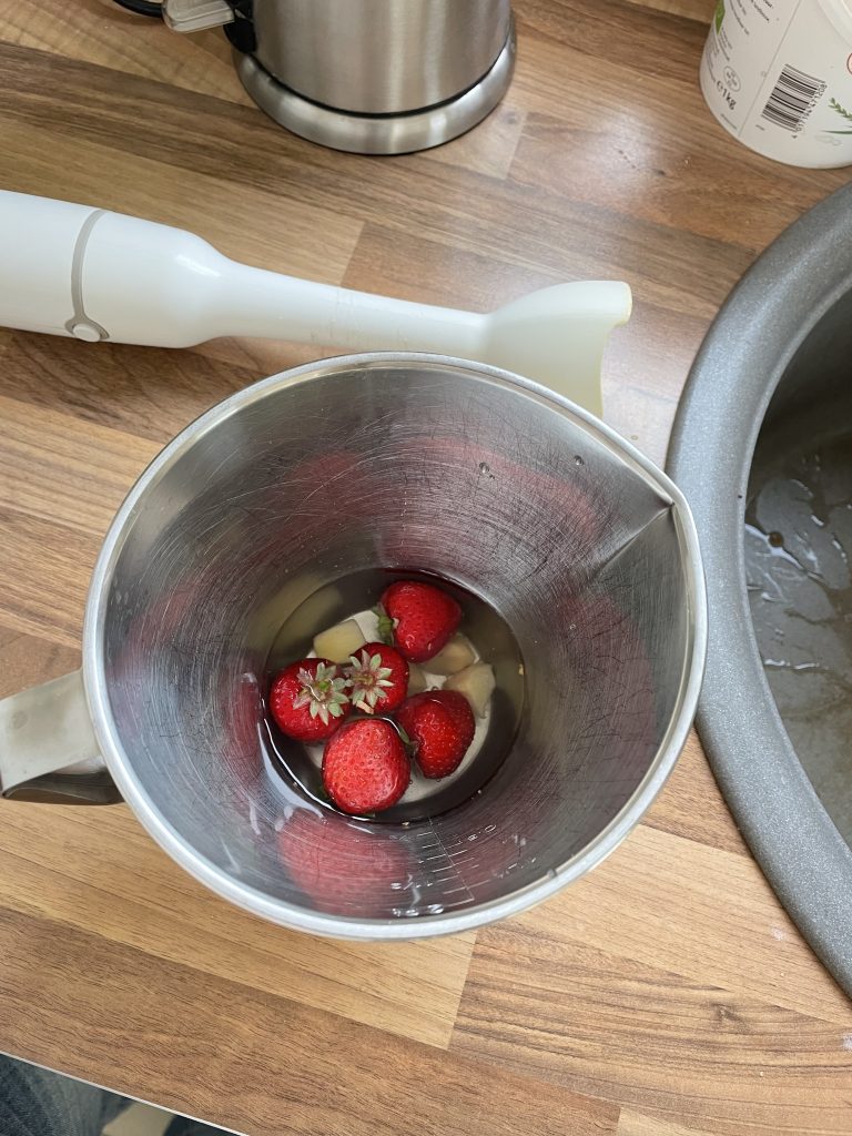 Erdbeeren und Ingwerstücke in einem Behältnis dort wird es gleich gemixt.