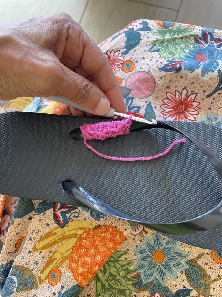 Ein Flip-Flop der mit einer pinkfarbenen Wolle umhäkelt wird