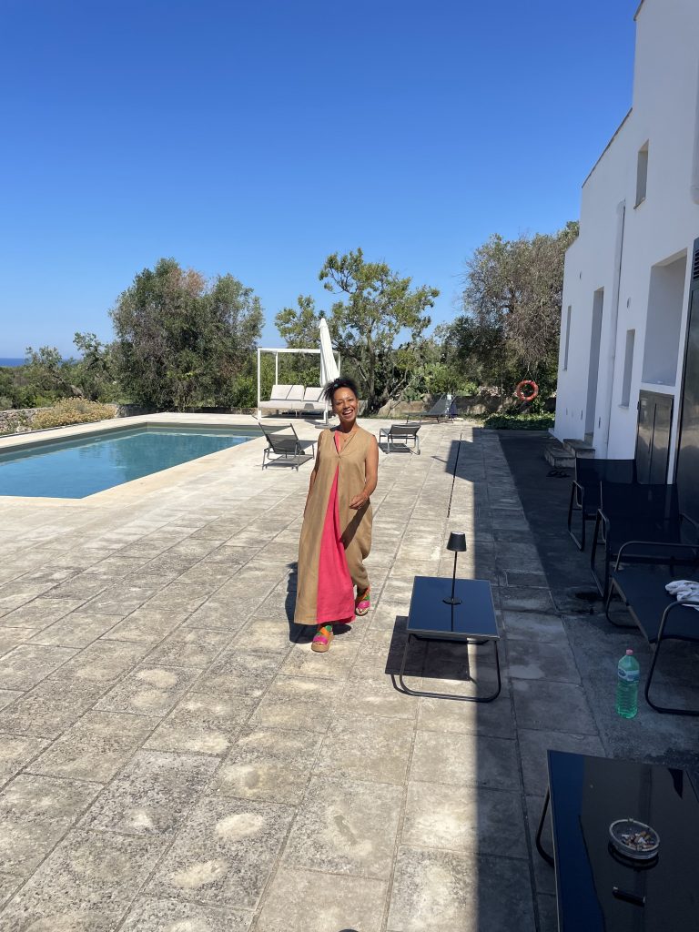 eine Frau läuft neben einem Pool in einem langen Kleid