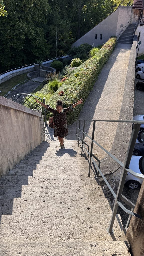 Eine Frau läuft eine Treppe hinauf hinter ihr sind Pflanzen und eine Wiese.