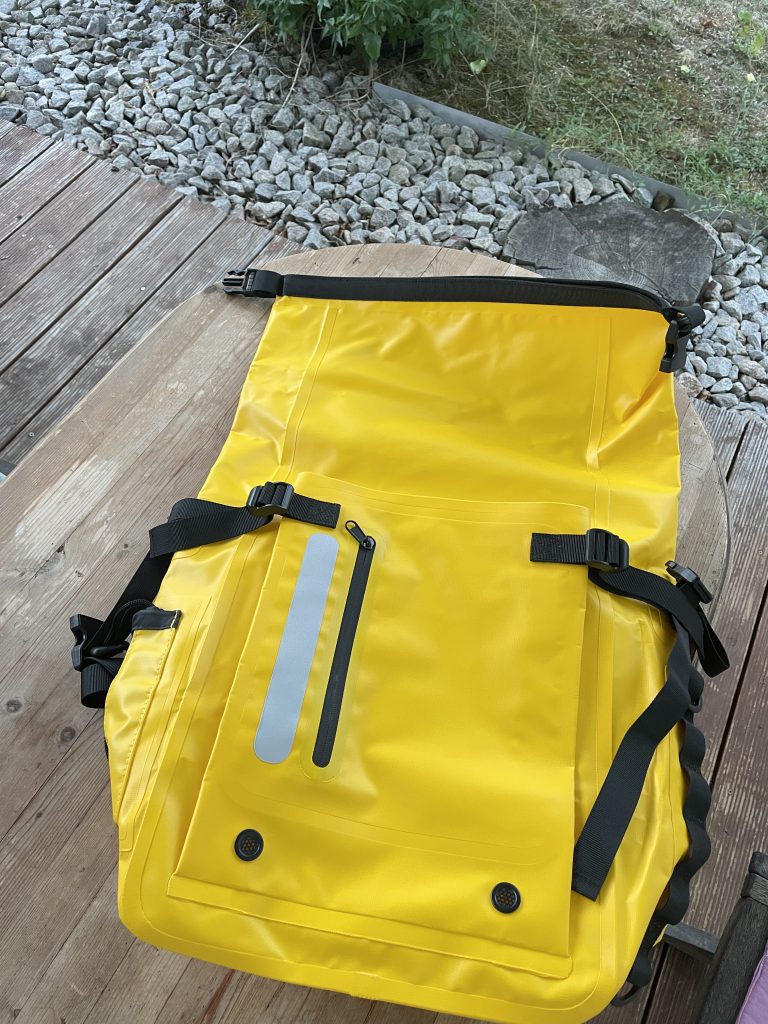 ei gelber Rolltoprucksack liegt auf einem Tisch