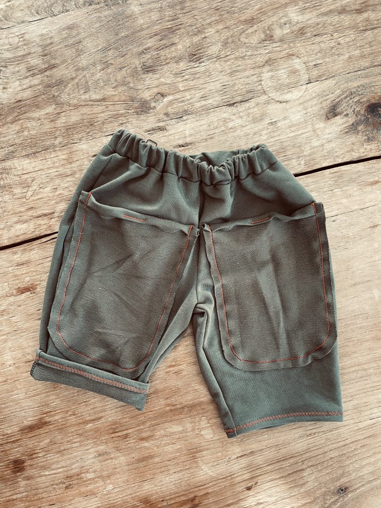 Babyhose aus grünem Sommersweat liegt auf einem Holztisch