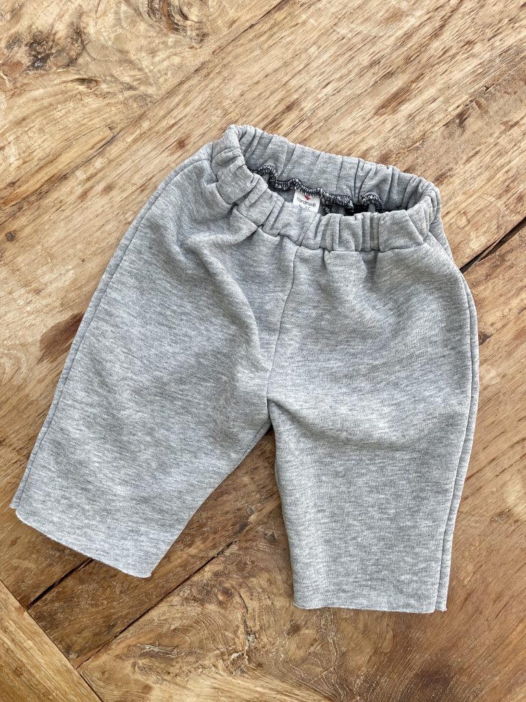 Babyhose aus grauem Stoff legt auf einem Holztisch