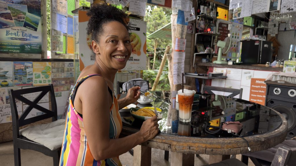 "Ronnies Organic Coconut Garden" Koh Chang. Eine Frau sitzt am Tisch und ißt und trinkt "Iced Thai Tea" und "Mango Stick Rice"