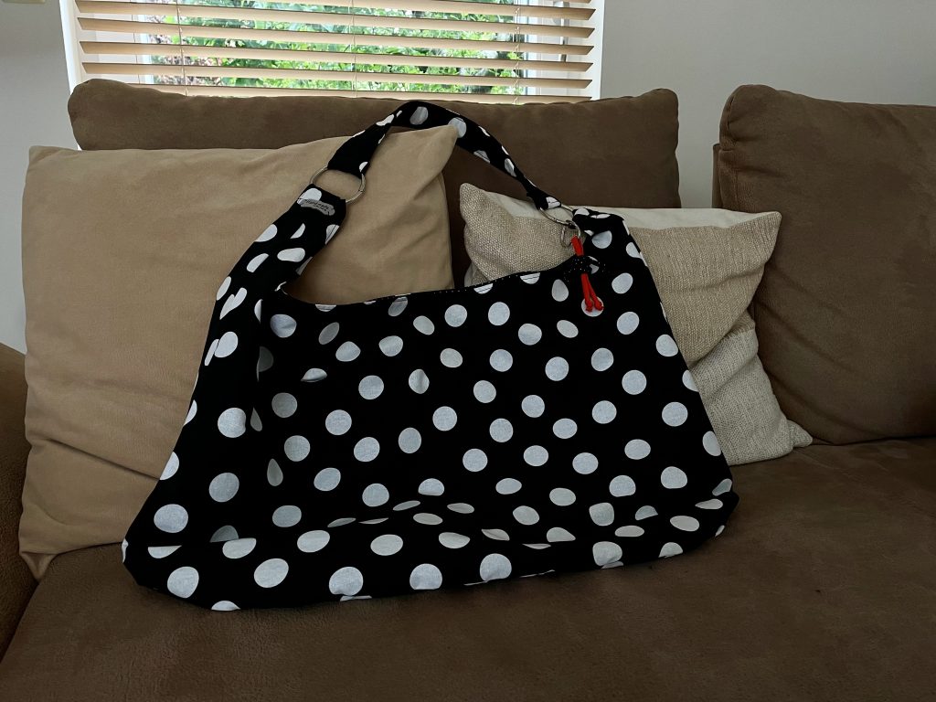 Ein große scharfe Tasche mit großen weißen Punkten liegt auf einem Sofa