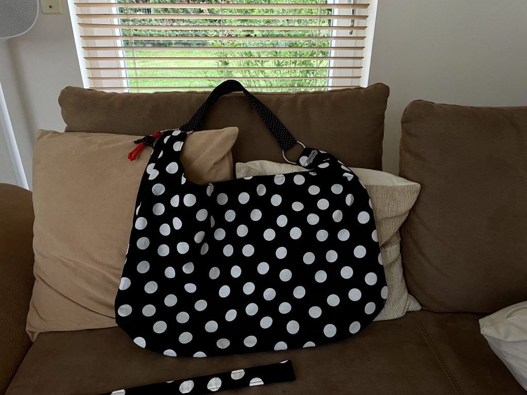 Ein große scharfe Tasche mit großen weißen Punkten liegt auf einem Sofa