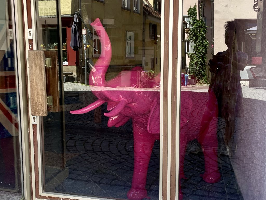 Ein rosafarbener Plastik-Elefant steht in einem Schaufenster