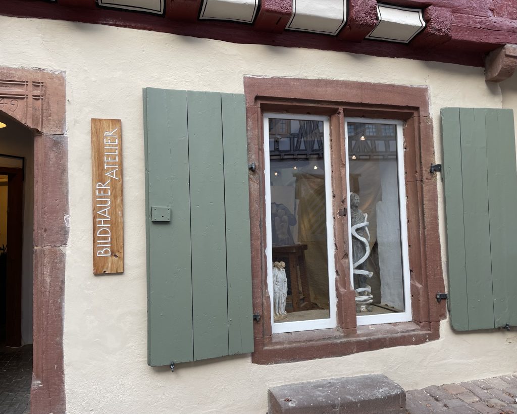 Ein Fenster mit grünen Fensterläden im Inneren kann man Skulpturen sehen