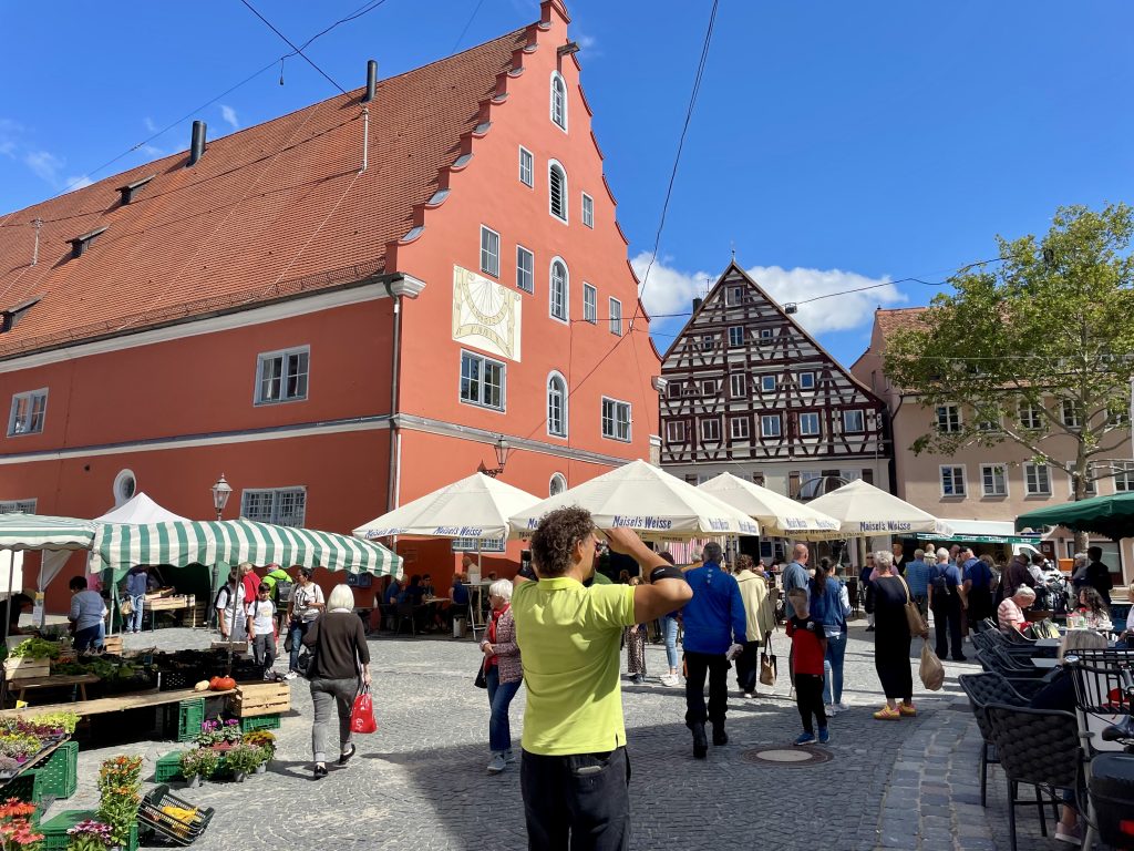 Wochenmarkt in Nördlingen auf dem Marktplatz vor historischen Fachwerkhäusern – buntes Markttreiben mit regionalen Produkten in der Altstadt von Nördlingen, Bayern.