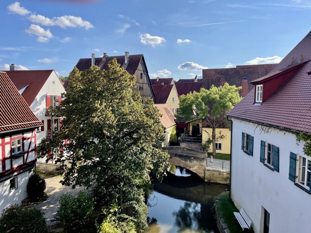 Mittelalterliche Häuser zwischen denen ein breiter Bach fließt mitteile kleinen Brücke