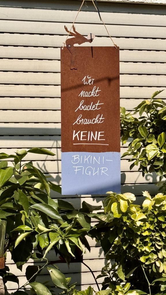 Ein Schild auf dem steht folgere Spruch: Wer nackt badet, braucht keine Bikinifigur