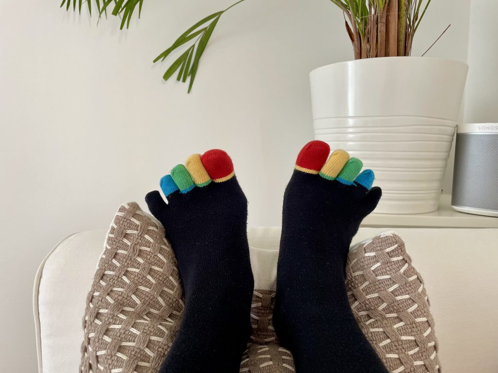 2 Füße mit Zehensocken. Jeder Sah hat eine andere Farbe