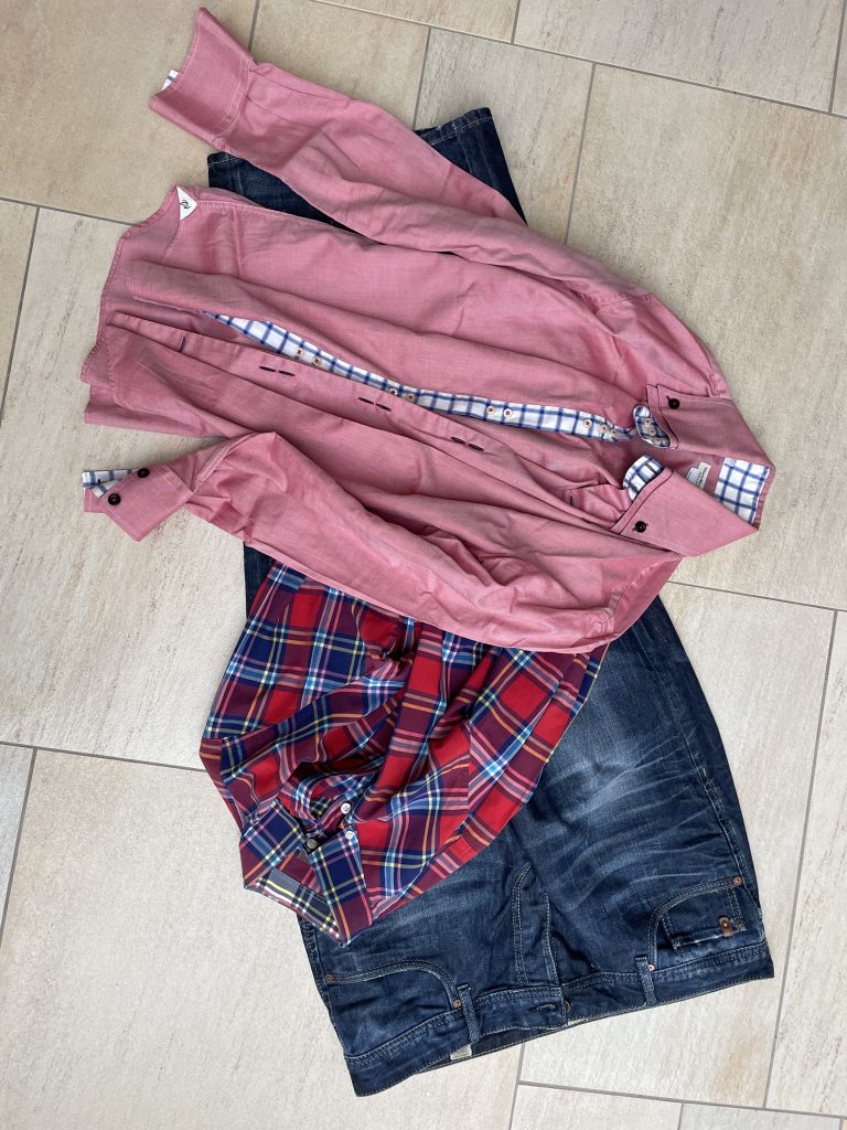 Eine Jeans, und zwei Herrenhemden liegen auf dem Boden