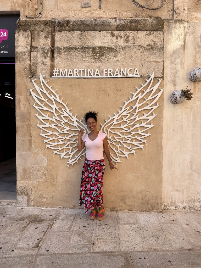 Martina Fanca eine Frau steht vor Engelsgeflügeln an einer Wand