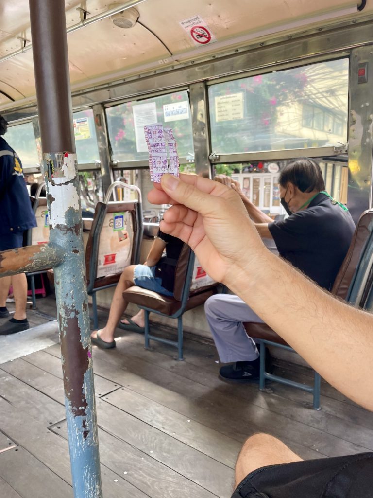 Im Bus in Bangkok in Thailand hält jemand seinen Fahrschein in der Hand hoch